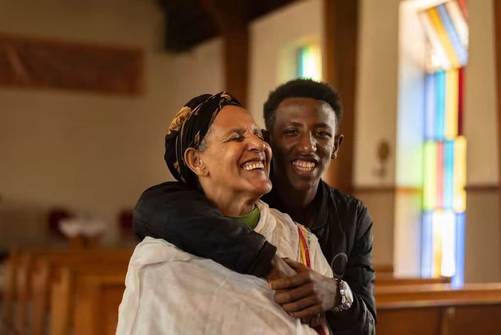 Ein Junge in Äthiopien und seine Grossmutter sitzen in einer Kirche und umarmen sich.