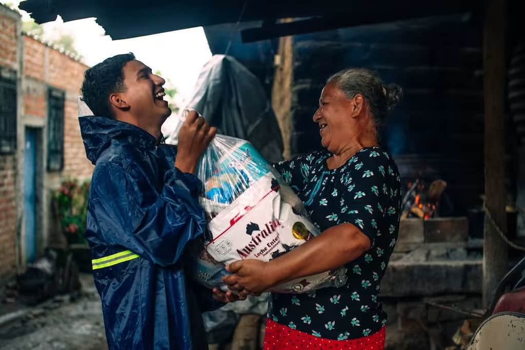 Au Salvador, un garçon remet un sac de provisions à un voisin âgé.