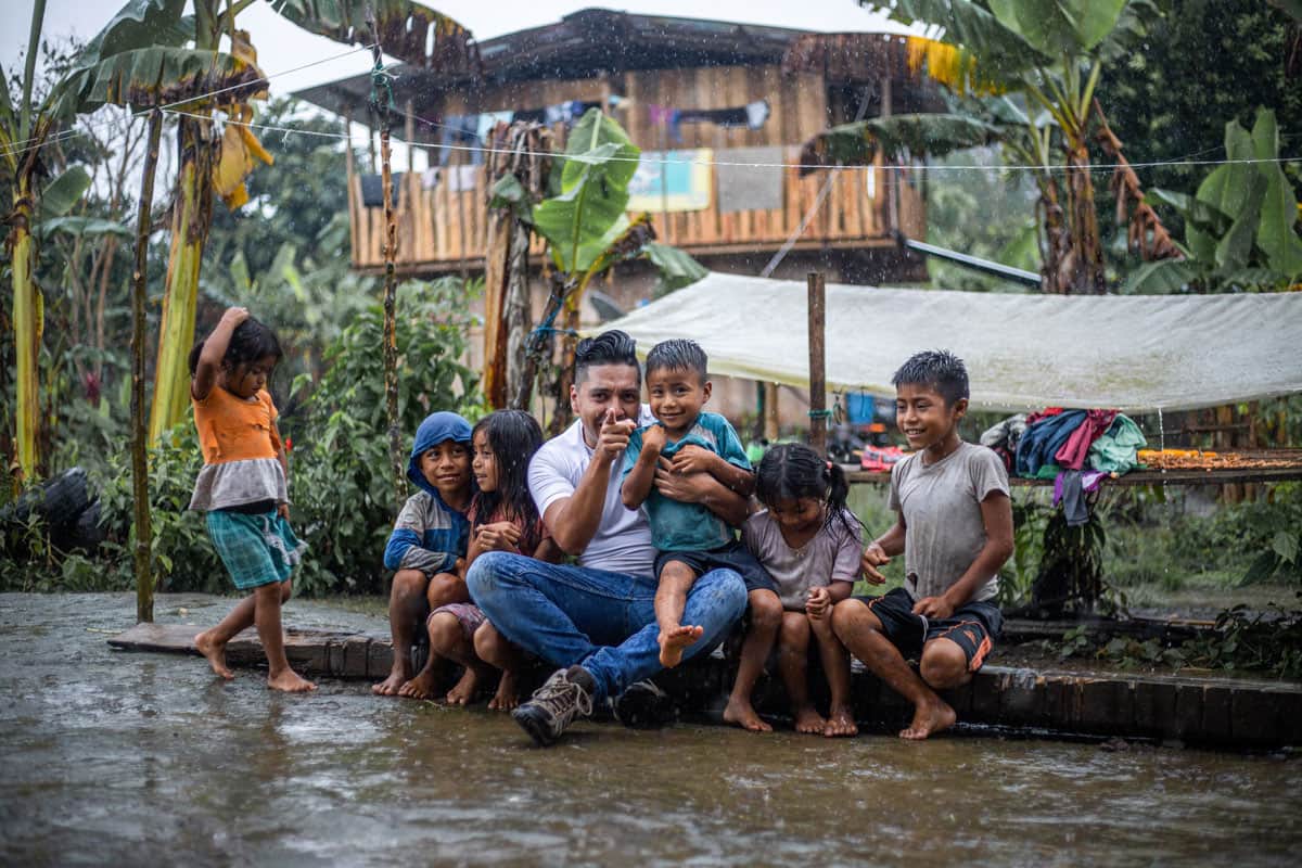 Compassion - Nico est assis sous la pluie avec des enfants dont il recueille les témoignages.