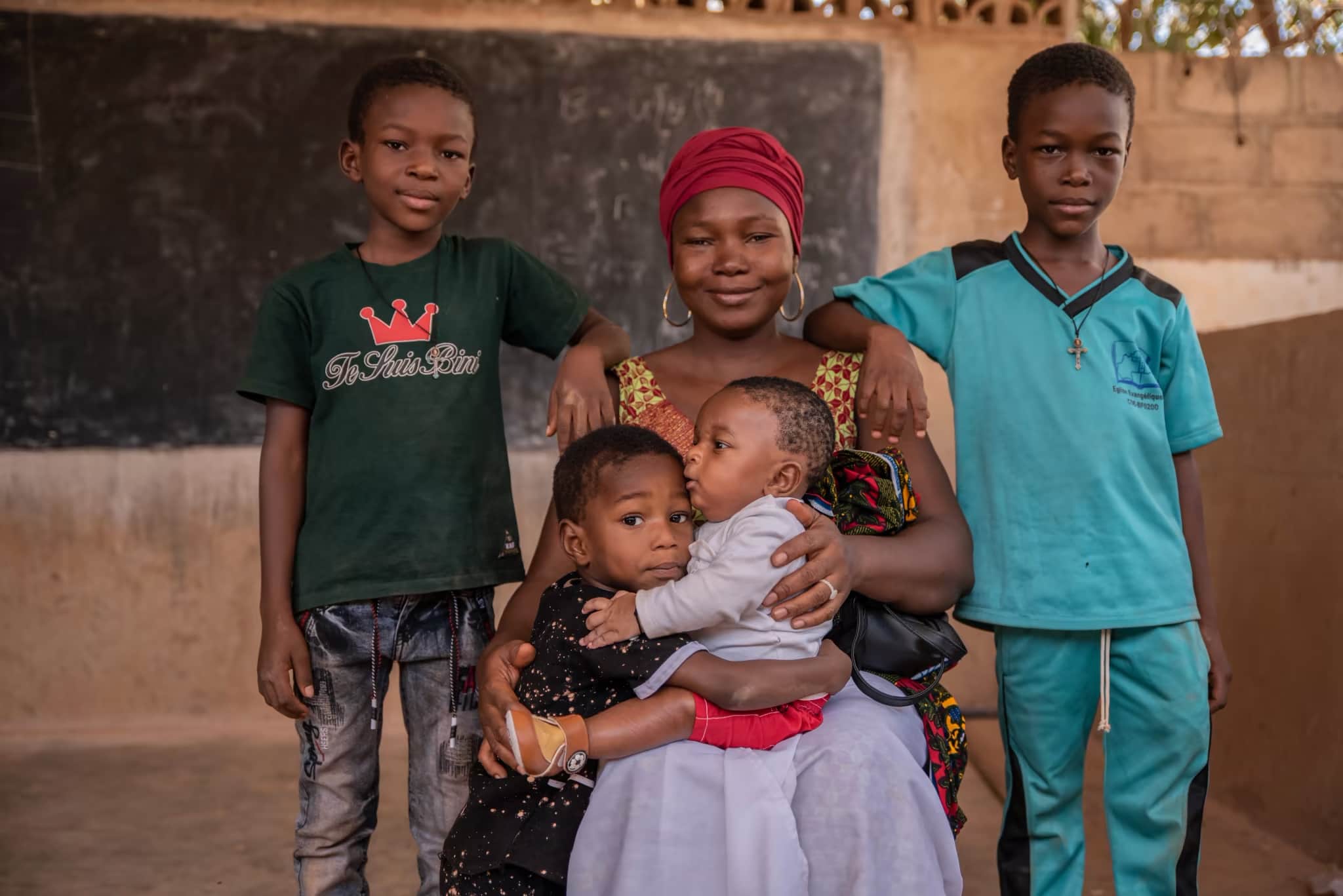 Parrainage d'enfants - Une maman du Burkina Faso assise avec ses quatre enfants qui lui sourient et l'entourent